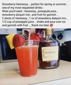 a bottle of hennesy next to a glass with strawberries on it