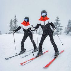 two skiers in black and red are posing for the camera