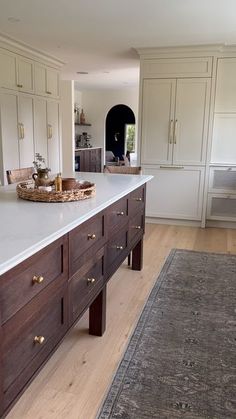 a large kitchen with white counters and wooden cabinets on the wall, along with an area rug