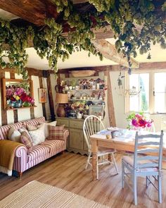 a living room filled with furniture and lots of greenery hanging from the ceiling above