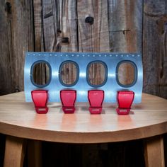 four red cups sitting on top of a wooden table next to a metal holder with holes in it