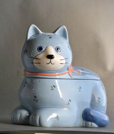 a blue cat shaped cookie jar sitting on top of a counter next to a wall