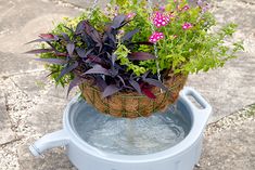 a basket filled with flowers sitting on top of a water fountain