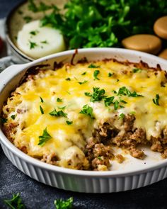 a casserole dish with meat, cheese and parsley in it on a table