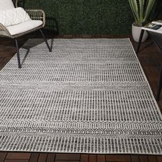 an outdoor area rug with two chairs and a potted plant