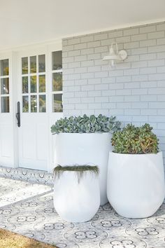 two large white planters sitting on the side of a house