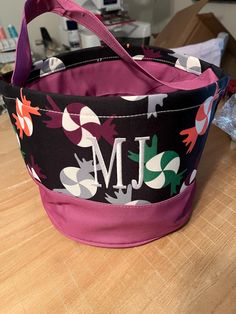 a pink and black flowered bag sitting on top of a wooden table