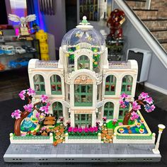 a lego model of a building with flowers and trees on the front, sitting on top of a table