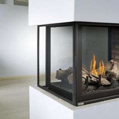 a fire place with logs and flames in the center, sitting on top of a white pedestal