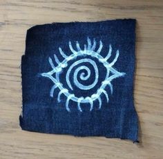 a piece of cloth with an eye drawn on it sitting on top of a wooden table