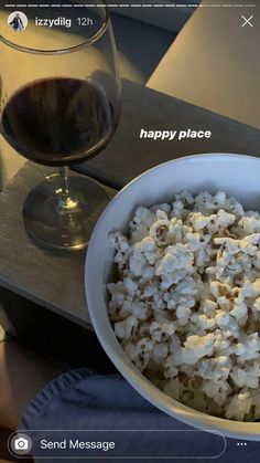 a bowl of popcorn next to a glass of wine on a table with the caption happy place