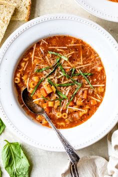 two bowls of pasta soup with bread on the side