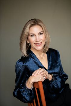 a woman with blonde hair is posing for a photo in a blue blouse and gold hoop earrings