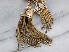 A breathtaking treasure from the Victorian era, this antique necklace is truly a collector's piece! Dating to the late 1800s or early 1900s, this Victorian necklace was intended for a ladies pendant watch or chatelaine, this chain features a quality of construction that is nearly impossible to find in modern markets. Decorative links weave together to form a single strand. The fobs feature gorgeous black enamel details on the cap, while the tassels are woven wires, with the caps holding them in Victorian Necklace, Gold Lariat Necklace, Pendant Watch, Gothic Victorian, Necklace Antique, Pendant Watches, Jewelry Antique, Cameo Ring, Right Hand Rings