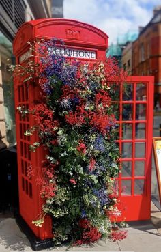 a red phone booth with flowers growing out of it