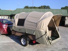 a trailer with a tent attached to it parked next to a car