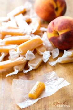 two peaches and some pieces of fruit on a wooden table with plastic wrappers