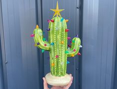 a person holding up a fake cactus with lights on it