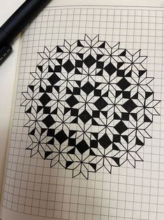 a pen is laying on top of a notebook with an intricate design in the middle