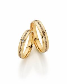 two yellow gold wedding rings with diamonds on each one, set against a white background