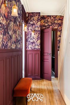 the hallway is decorated in purple and orange with floral wallpaper, along with an orange bench