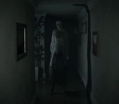 a woman walking down a hallway in the dark