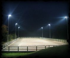 an empty arena at night with lights shining on the ground and grass in the foreground