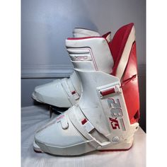 a pair of white and red ski boots sitting on top of a table next to a wall