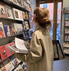 a woman is looking at books in a book store