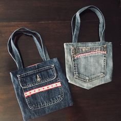 two denim bags sitting next to each other on a wooden table and one has a pocket