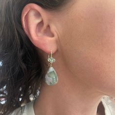 This stunning pair of Aquaprase™ drop earrings are for the lover of stones. Paired with our signature crownwork® clover earring tops set with green sapphires. The clover is often associated with good luck and positive reinforcement. Our 18k spring wire hooks are high tensile making them slip on and off, the clover design completes the earring with a spread of color and the scalloped edge is a stylish way to highlight the stones. MATERIAL: 18k Yellow Gold STONE TYPE/CARAT WEIGHT: Green Sapphire 0.88cts, Aquaprase™ 48.1cts DIMENSIONS: 1.5" Green Sapphire Drop Earrings, Green Sterling Silver Earrings With Sparkling Stones, Green Natural Stones Drop Earrings, Green Faceted Teardrop Earrings, Nickel-free Green Sterling Silver Crystal Earrings, 45th Wedding Anniversary, Swords Medieval, Clover Earrings, Green Sapphire