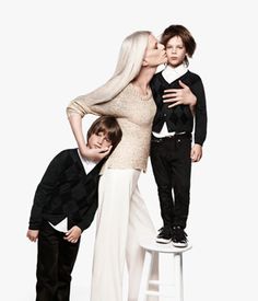 a woman and two boys are kissing while standing on a stool