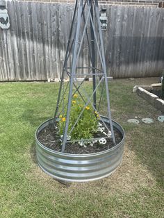 a metal planter with flowers in it sitting on the grass next to a fence