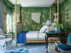 a bedroom decorated in green and blue with floral wallpaper, gold canopy bed frame