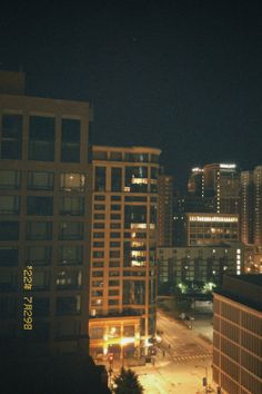 the city skyline is lit up at night with buildings and street lights in the foreground