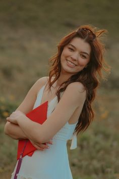 a young woman standing in a field with her arms crossed