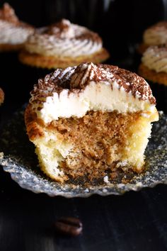 a cupcake with white frosting and chocolate sprinkles is on a plate