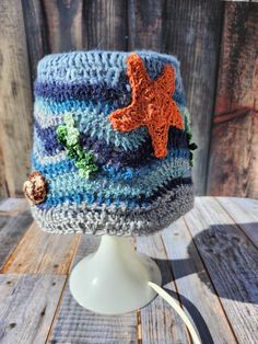 a crocheted hat with an orange starfish on the top and blue stripes