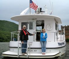 two people standing on the front of a white boat with an american flag on it