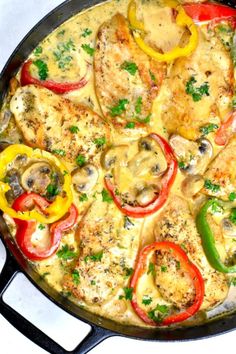 a skillet filled with chicken, peppers and mushrooms on top of a white table