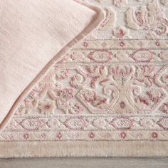 an area rug with pink and white designs on the top is laying on a wooden floor