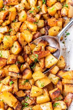 a pan filled with cooked potatoes and garnished with parsley on the side