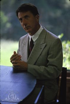 a man in a suit and tie sitting at a table with his hands folded up