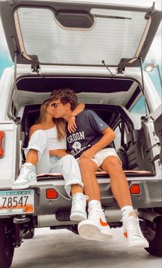 two people sitting in the back of a pick up truck with their arms around each other