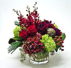 a glass vase filled with red and green flowers