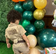 a little boy standing in front of balloons