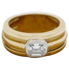 This lovely Tiffany & Co. vintage diamond ring from 1995, is crafted in vibrant 18k yellow gold. This classic piece features a beautiful emerald cut diamond at the center of a wide, ridged band, set horizontally along the ring, resting within a raised bezel setting crafted in platinum. The wide band has deep grooves which carry along the surface, graduating slightly towards the back, providing a dramatic textured appeal. Stamped inside the shank is the official "Tiffany & Co" signature hallmark, Vintage Diamond Ring, Tiffany Diamond, Wide Band Ring, Emerald Diamond Ring, Vintage Diamond Rings, Emerald Cut Diamond, Diamond Cocktail Rings, Platinum Engagement Rings, Gold Band Ring