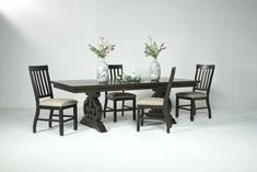 a dining table with four chairs and a vase filled with flowers on the top shelf