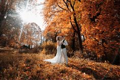 a bride and groom are standing in the woods