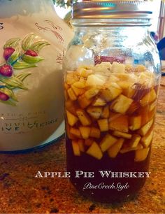 apple pie whiskey in a glass jar on a counter top next to a canister